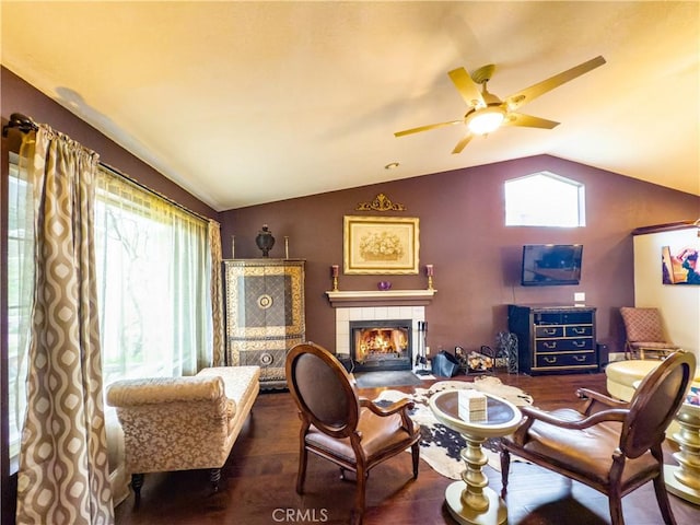 living area featuring a tile fireplace, a healthy amount of sunlight, vaulted ceiling, and wood finished floors