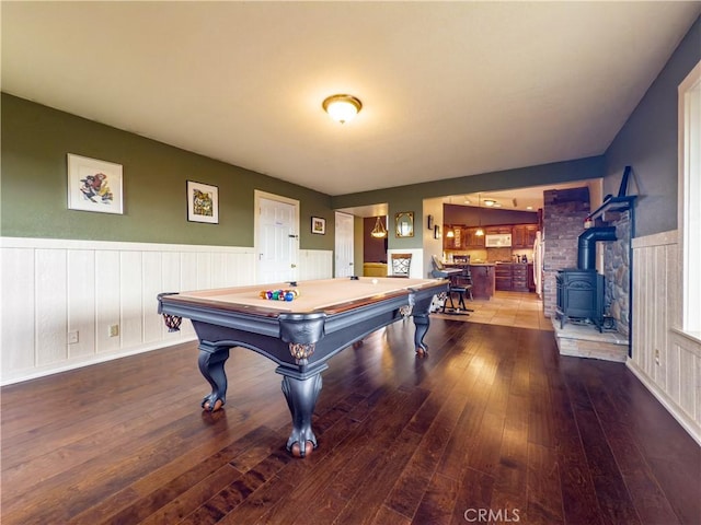 rec room featuring a wood stove, a wainscoted wall, wood-type flooring, and pool table