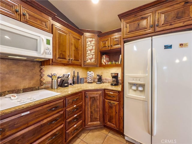 kitchen with light stone counters, white appliances, brown cabinetry, and light tile patterned floors