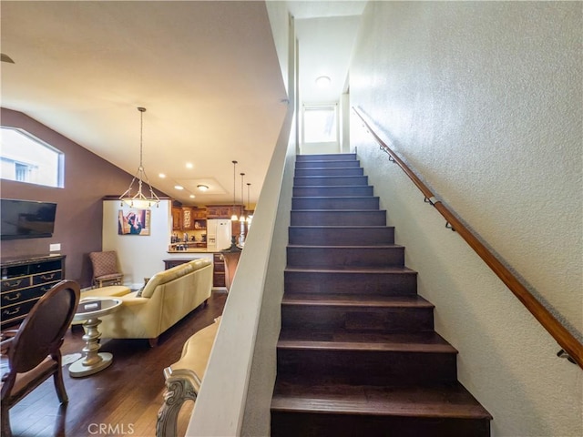 stairs with vaulted ceiling, a textured wall, and wood finished floors