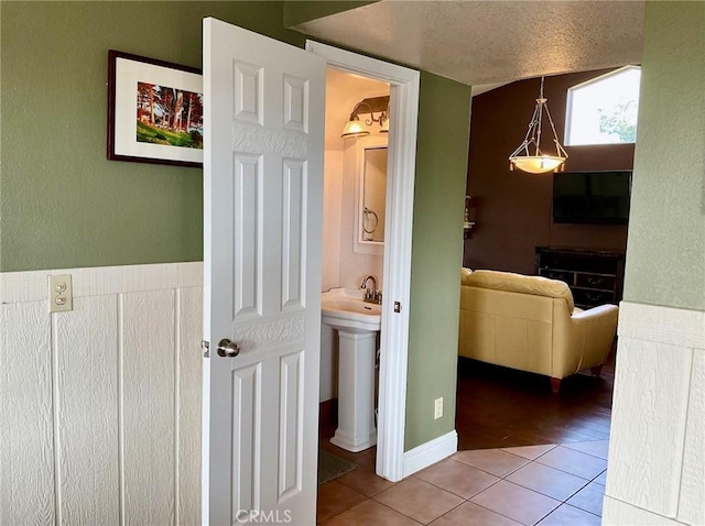 hall with a textured ceiling and tile patterned floors