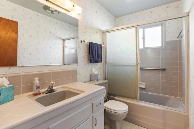 full bathroom with combined bath / shower with glass door, vanity, toilet, and wallpapered walls