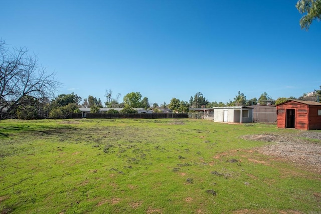 view of yard featuring a storage unit, an outdoor structure, and fence