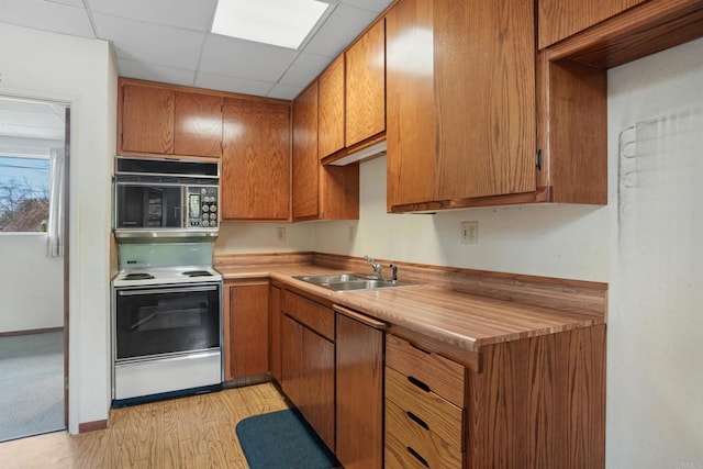 kitchen with black microwave, brown cabinets, a sink, and electric range oven