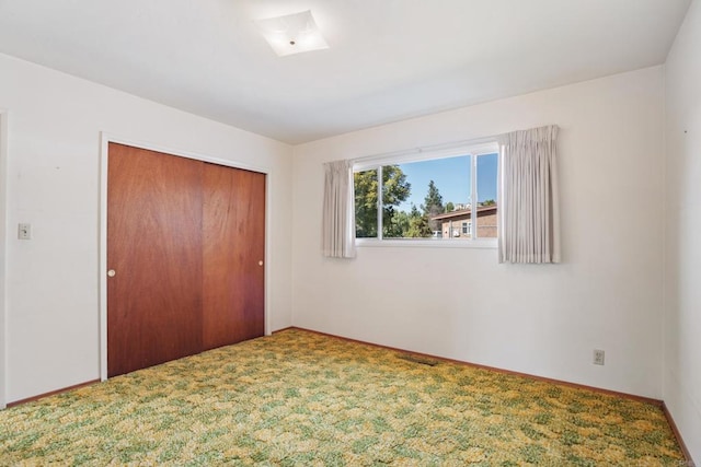 unfurnished bedroom featuring carpet, baseboards, and a closet