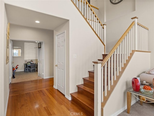 staircase featuring baseboards, wood finished floors, and recessed lighting