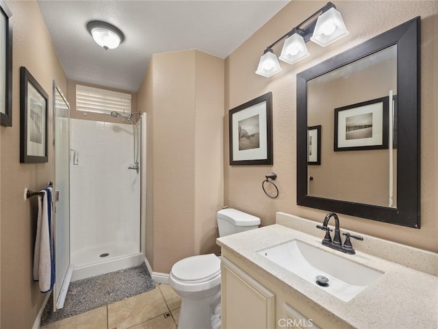 bathroom featuring tile patterned flooring, a tile shower, vanity, and toilet