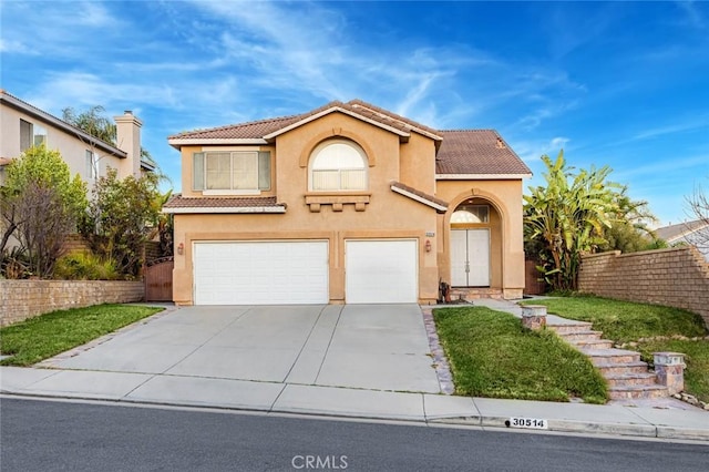 mediterranean / spanish-style home featuring driveway, a tile roof, an attached garage, fence, and stucco siding