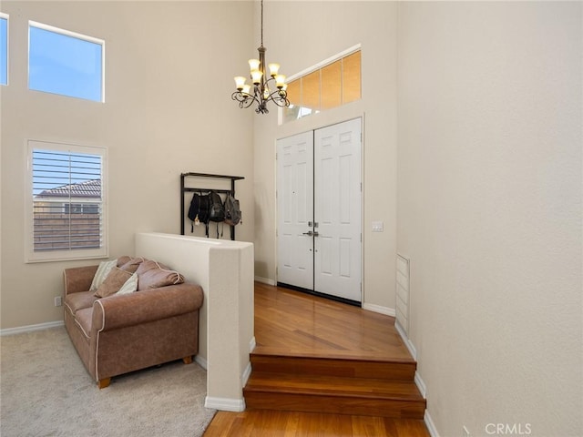 foyer with a high ceiling, baseboards, a notable chandelier, and wood finished floors