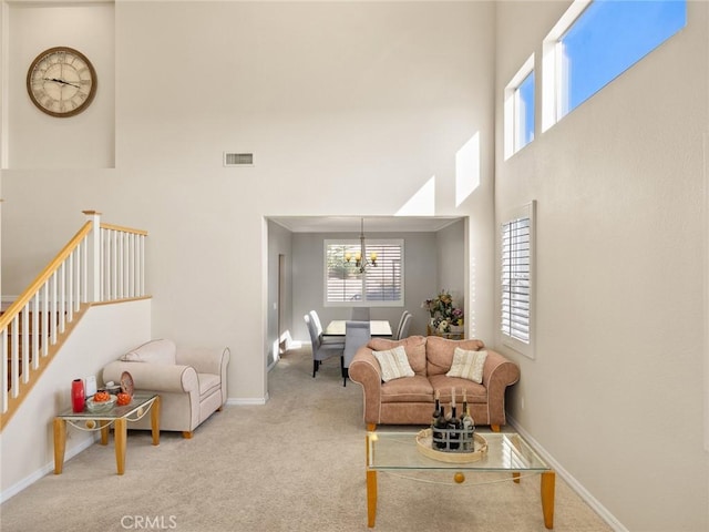 carpeted living area featuring a high ceiling, plenty of natural light, visible vents, and baseboards