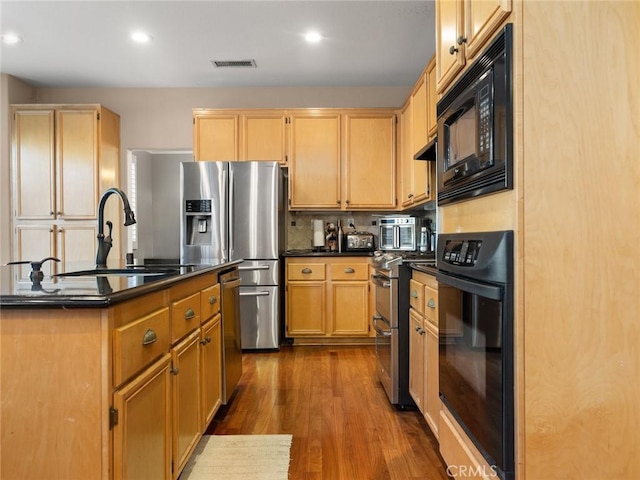 kitchen featuring a sink, light brown cabinetry, dark wood-style floors, black appliances, and dark countertops