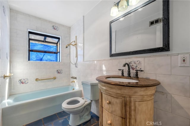 bathroom featuring shower / bathtub combination, toilet, visible vents, vanity, and tile walls