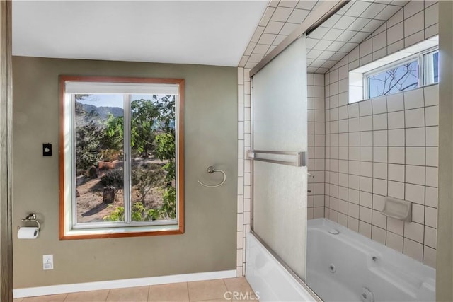 full bath with a combined bath / shower with jetted tub, plenty of natural light, baseboards, and tile patterned floors