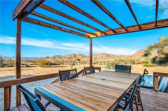 wooden deck with a mountain view, a pergola, and outdoor dining space