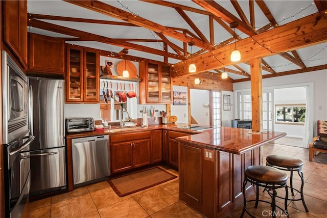 kitchen featuring a toaster, a kitchen breakfast bar, a peninsula, stainless steel appliances, and a sink