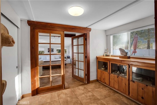 entryway with french doors, light tile patterned flooring, and baseboards