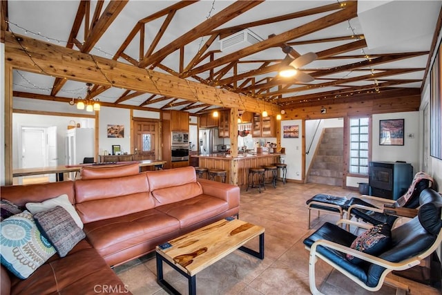 living area with vaulted ceiling with beams, visible vents, a wood stove, light tile patterned flooring, and stairs