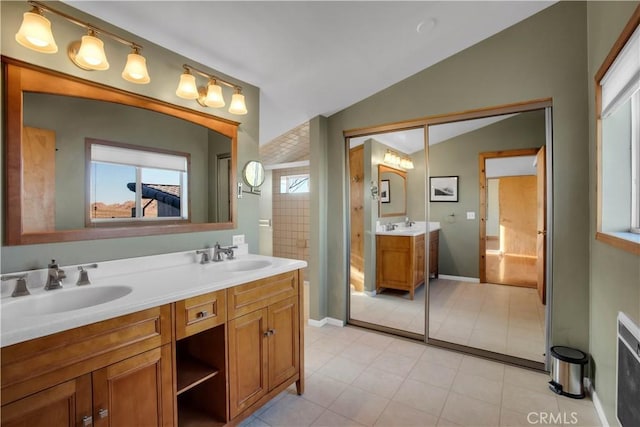 full bath featuring lofted ceiling, a sink, baseboards, and double vanity