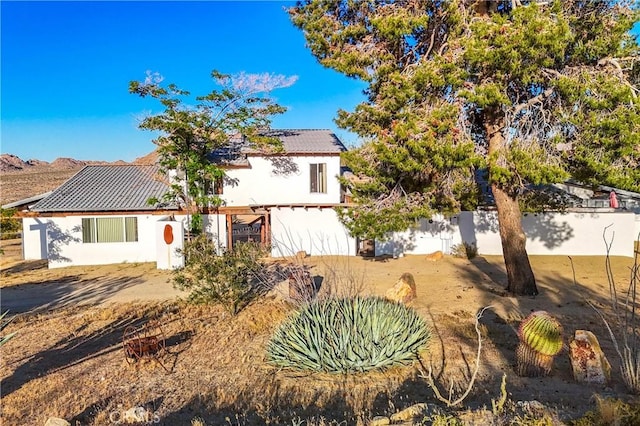 view of front of property featuring fence, solar panels, and stucco siding