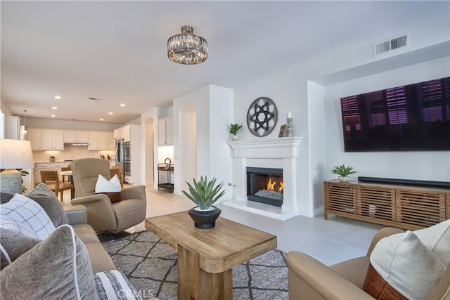 living room featuring baseboards, visible vents, an inviting chandelier, recessed lighting, and a lit fireplace