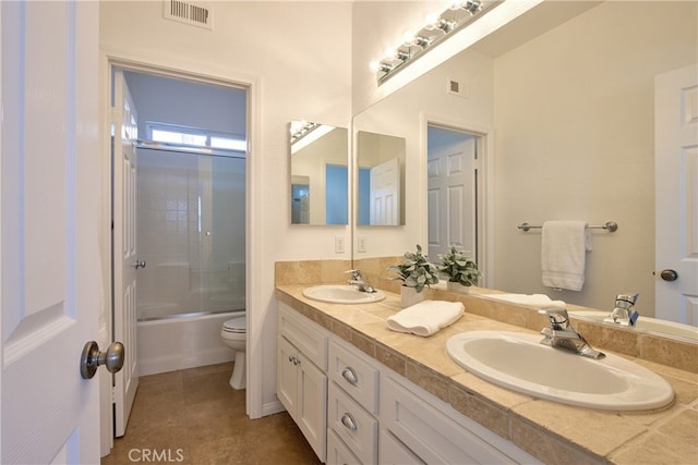 bathroom featuring double vanity, visible vents, toilet, and a sink