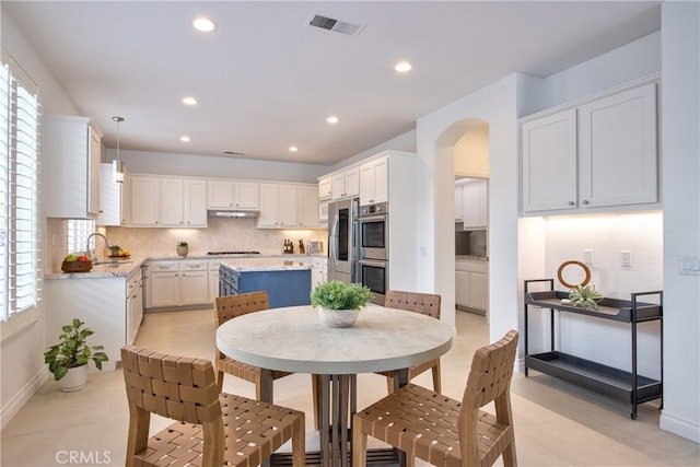 dining space with recessed lighting, visible vents, arched walkways, and plenty of natural light