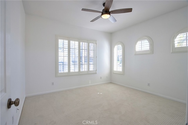 empty room featuring baseboards, light colored carpet, a healthy amount of sunlight, and a ceiling fan