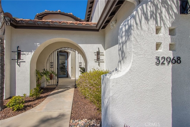 entrance to property with a tile roof and stucco siding