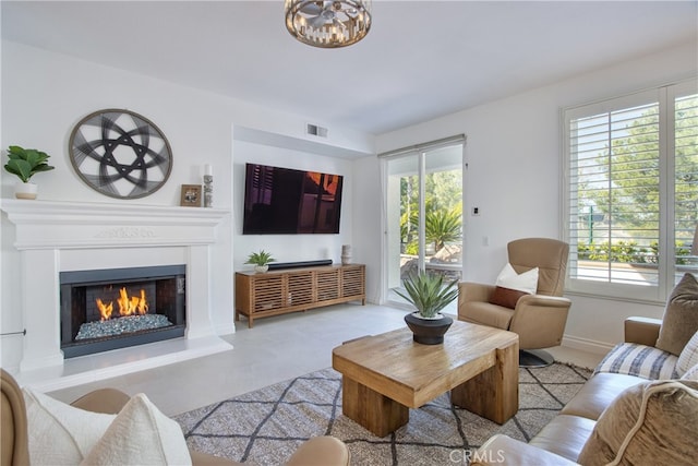 living area featuring baseboards, a healthy amount of sunlight, visible vents, and a lit fireplace