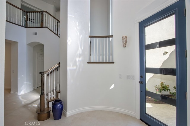 interior space with visible vents, arched walkways, baseboards, a towering ceiling, and stairs