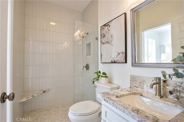 bathroom featuring toilet, vanity, and a tile shower