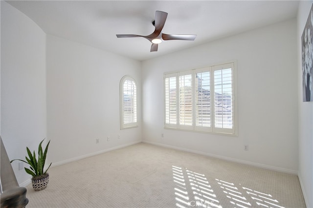 carpeted empty room featuring baseboards and a ceiling fan