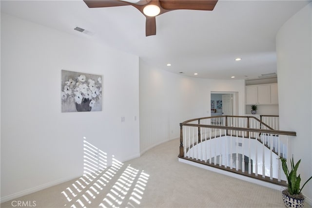 hall with an upstairs landing, visible vents, light colored carpet, and recessed lighting