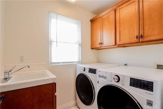 clothes washing area featuring a sink, washing machine and dryer, and cabinet space