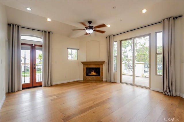 unfurnished living room with baseboards, a tiled fireplace, light wood-style flooring, ceiling fan, and recessed lighting