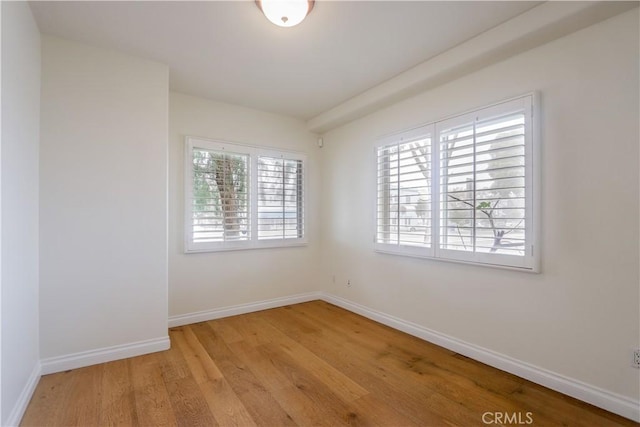 unfurnished room with baseboards and light wood-style floors