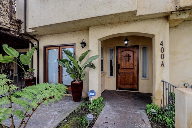 doorway to property with fence and stucco siding