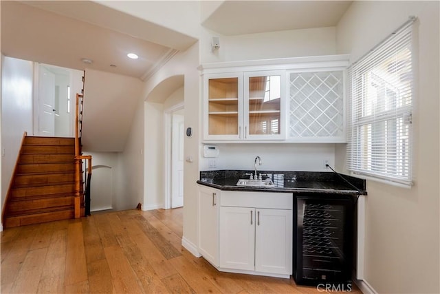 bar featuring beverage cooler, light wood-style flooring, stairway, a sink, and indoor wet bar