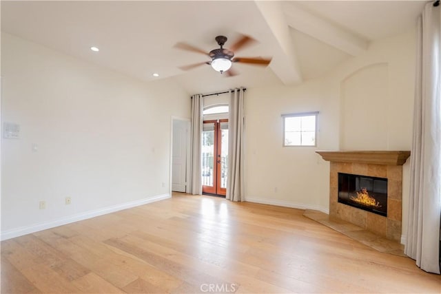 unfurnished living room featuring vaulted ceiling with beams, a tiled fireplace, baseboards, and light wood-style floors