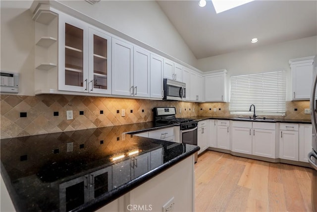 kitchen with appliances with stainless steel finishes, a sink, white cabinetry, and light wood-style floors