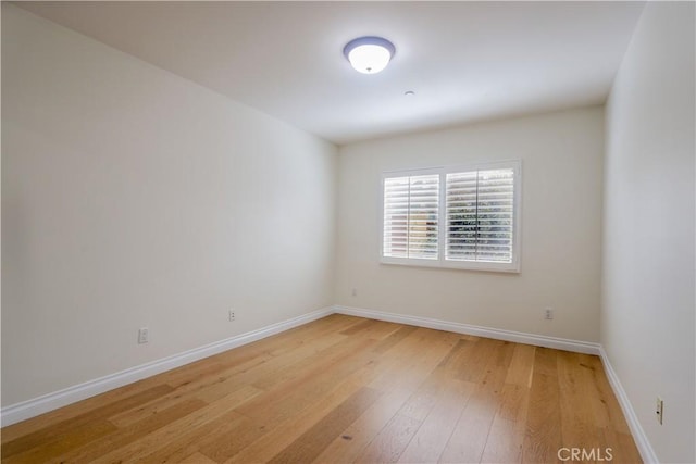 spare room featuring light wood-type flooring and baseboards