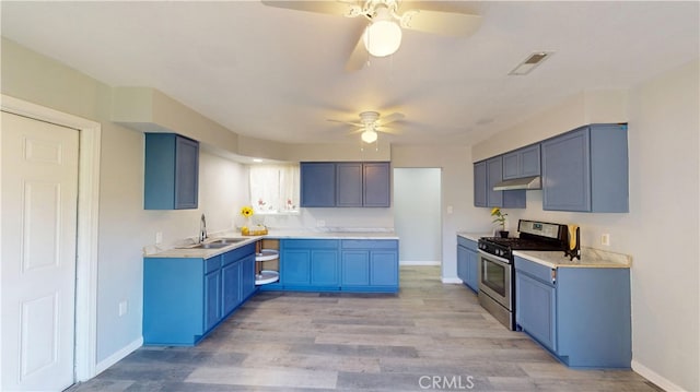 kitchen featuring blue cabinetry, visible vents, light wood-style floors, stainless steel range with gas stovetop, and a sink