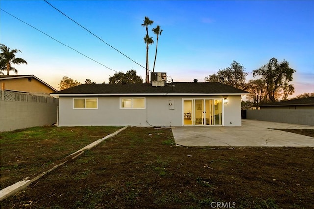 rear view of property featuring a patio, a lawn, fence, and stucco siding