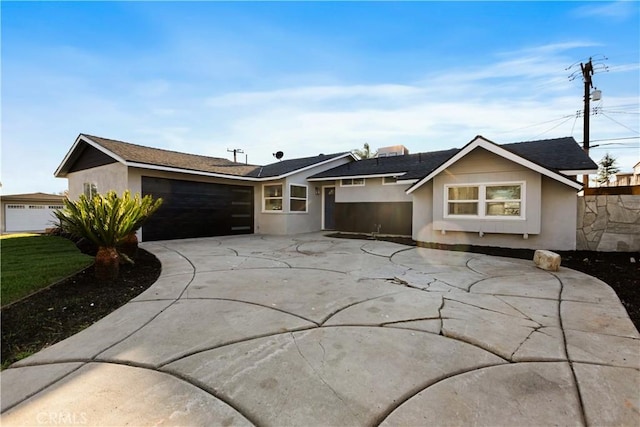 ranch-style house with driveway, fence, an attached garage, and stucco siding