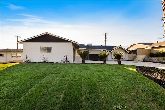 view of front of house with stucco siding, fence, concrete driveway, and a front yard