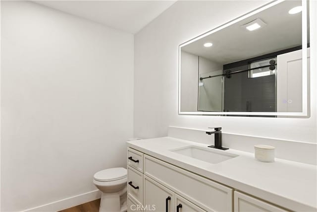 bathroom featuring toilet, an enclosed shower, vanity, wood finished floors, and baseboards