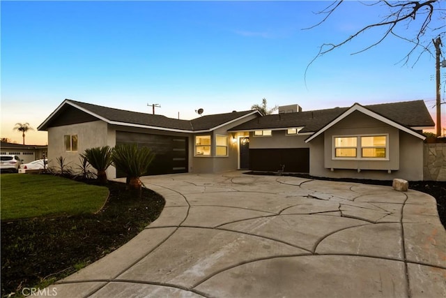 view of front of house with a garage, driveway, and stucco siding