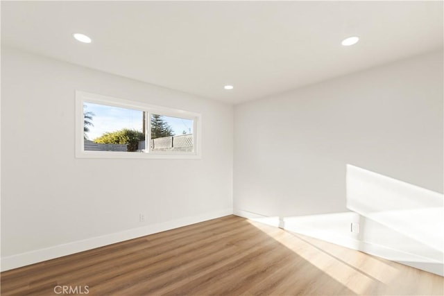 empty room featuring baseboards, wood finished floors, and recessed lighting