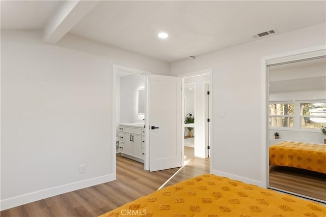 unfurnished bedroom featuring beam ceiling, wood finished floors, visible vents, and baseboards