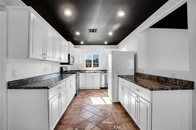 kitchen with stainless steel appliances, recessed lighting, dark countertops, and white cabinets